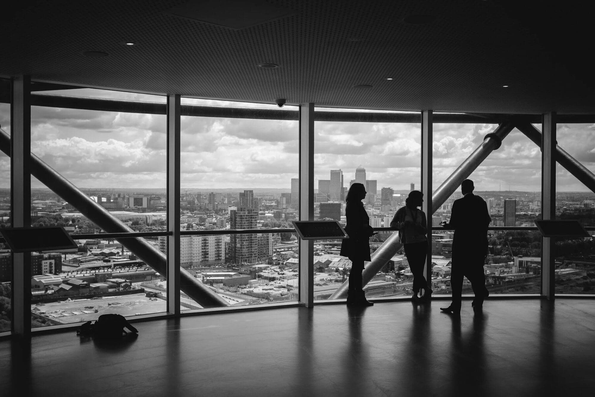 Silhouettes of people looking out over a city from a high-rise window